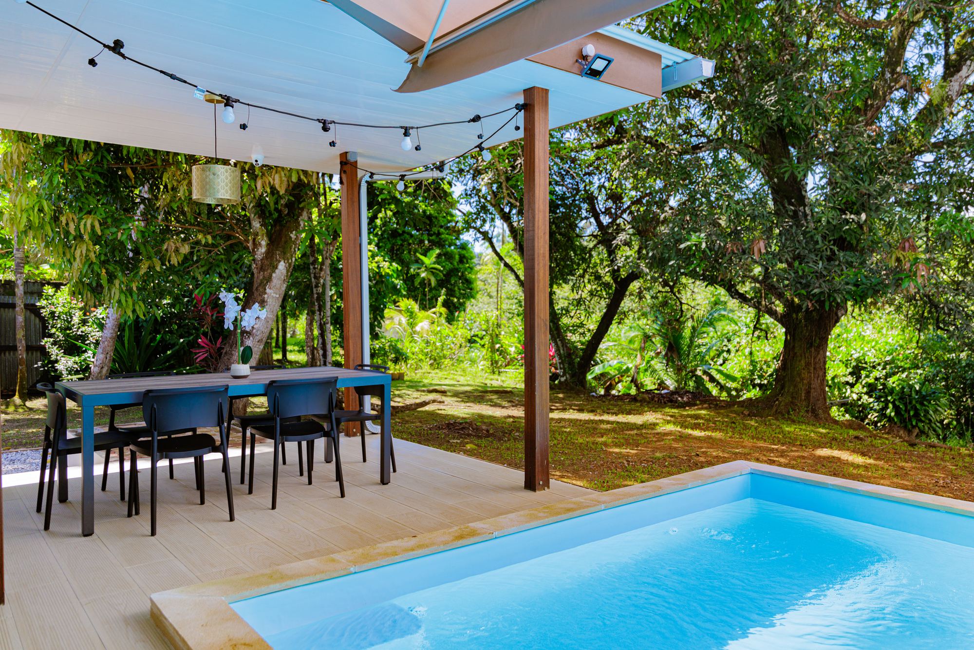 La terrasse et sa table, ouvertes sur le jardin tropical, au bord de la piscine